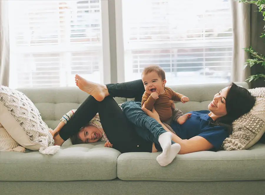 mother and two children having fun on the couch in her comfortable home - Decatur, IL